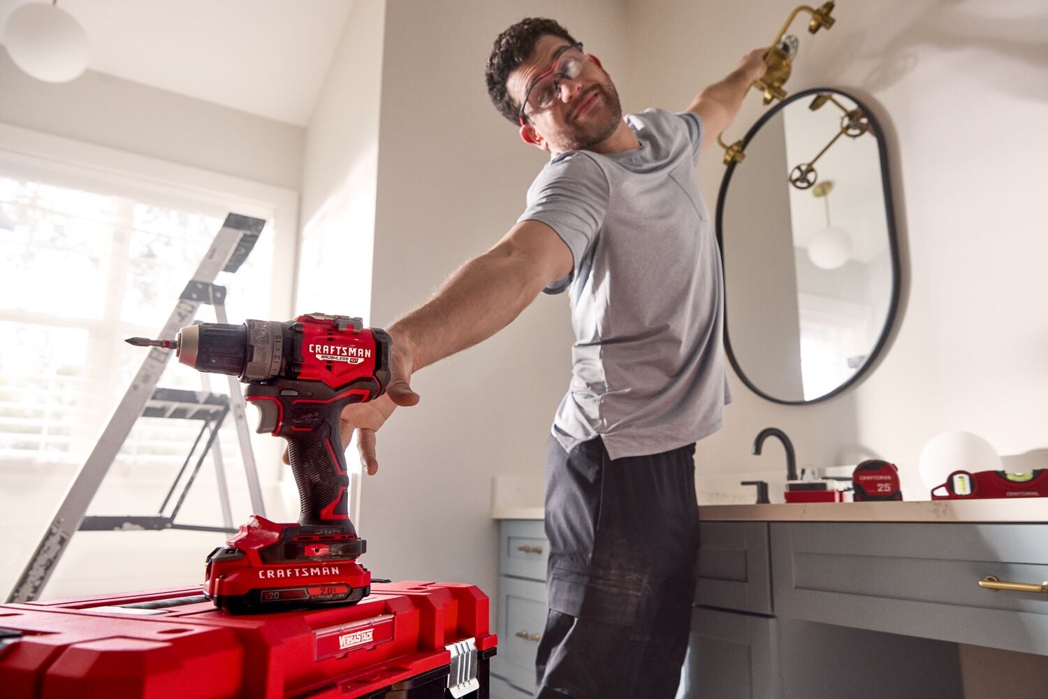 Photo of Craftsman cordless drill CMCD725D2 on red toolbox in bathroom workspace, person reaching for faucet.