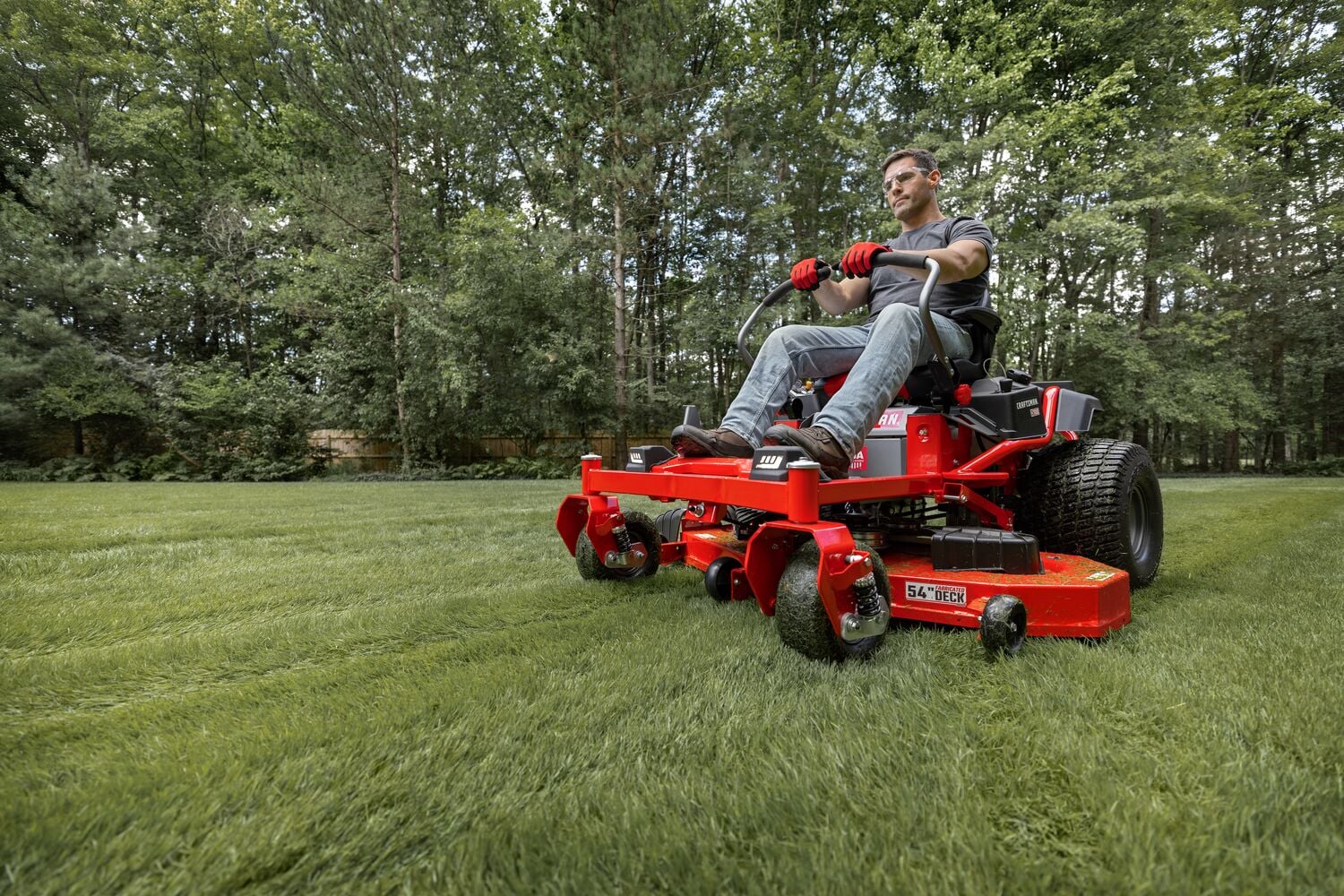 Photo of CRAFTSMAN zero-turn lawn mower CMGN231702 mowing grass outdoors, angled view, red color.