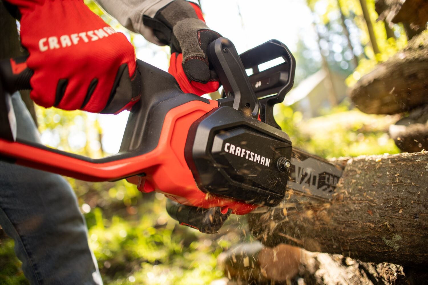 Photo of a CRAFTSMAN CMCCS630B cordless chainsaw cutting through a tree branch, operator wearing red gloves.