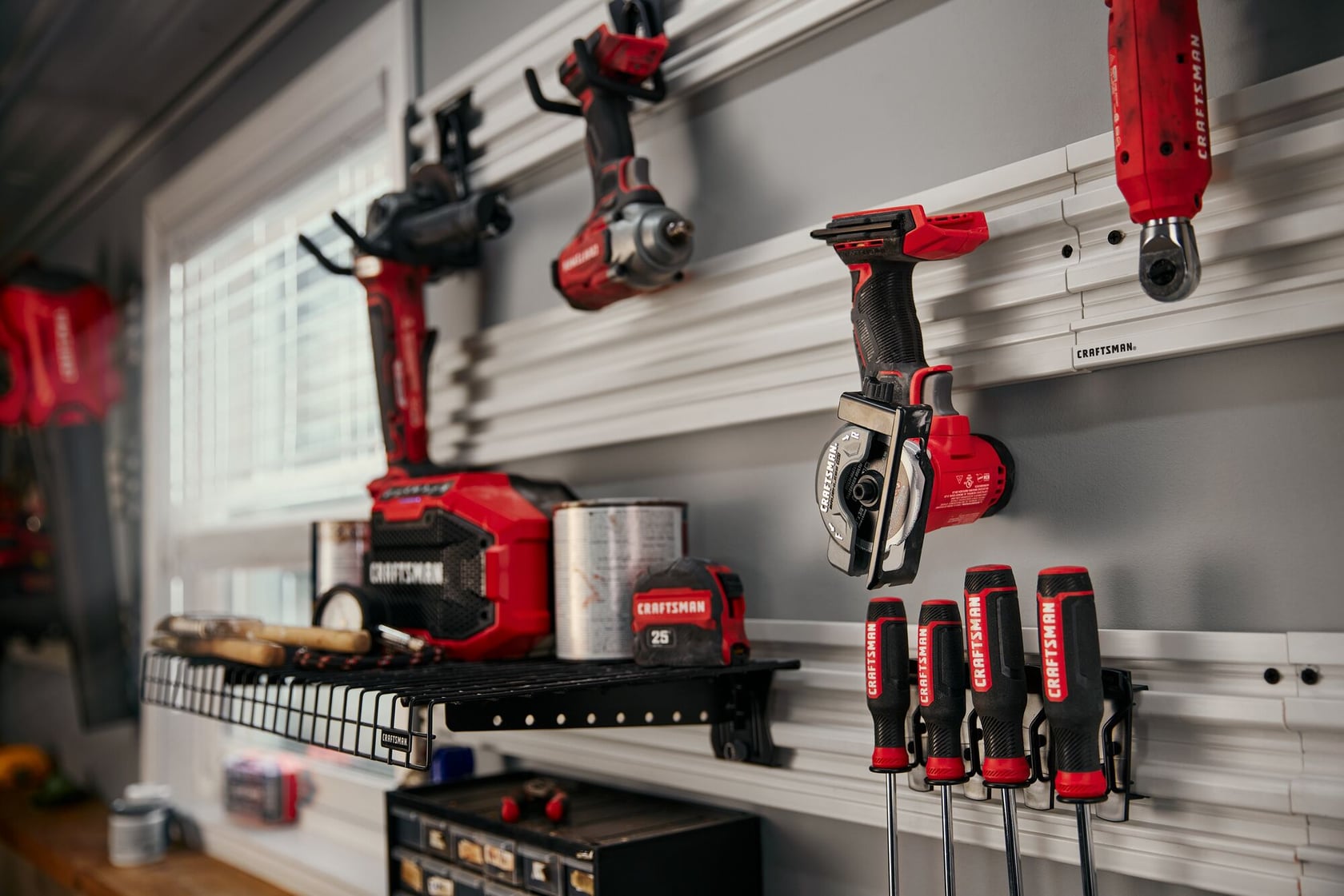 Craftsman CMCM300B power tools and hand tools in red and black on a wall-mounted organizer in a workshop.