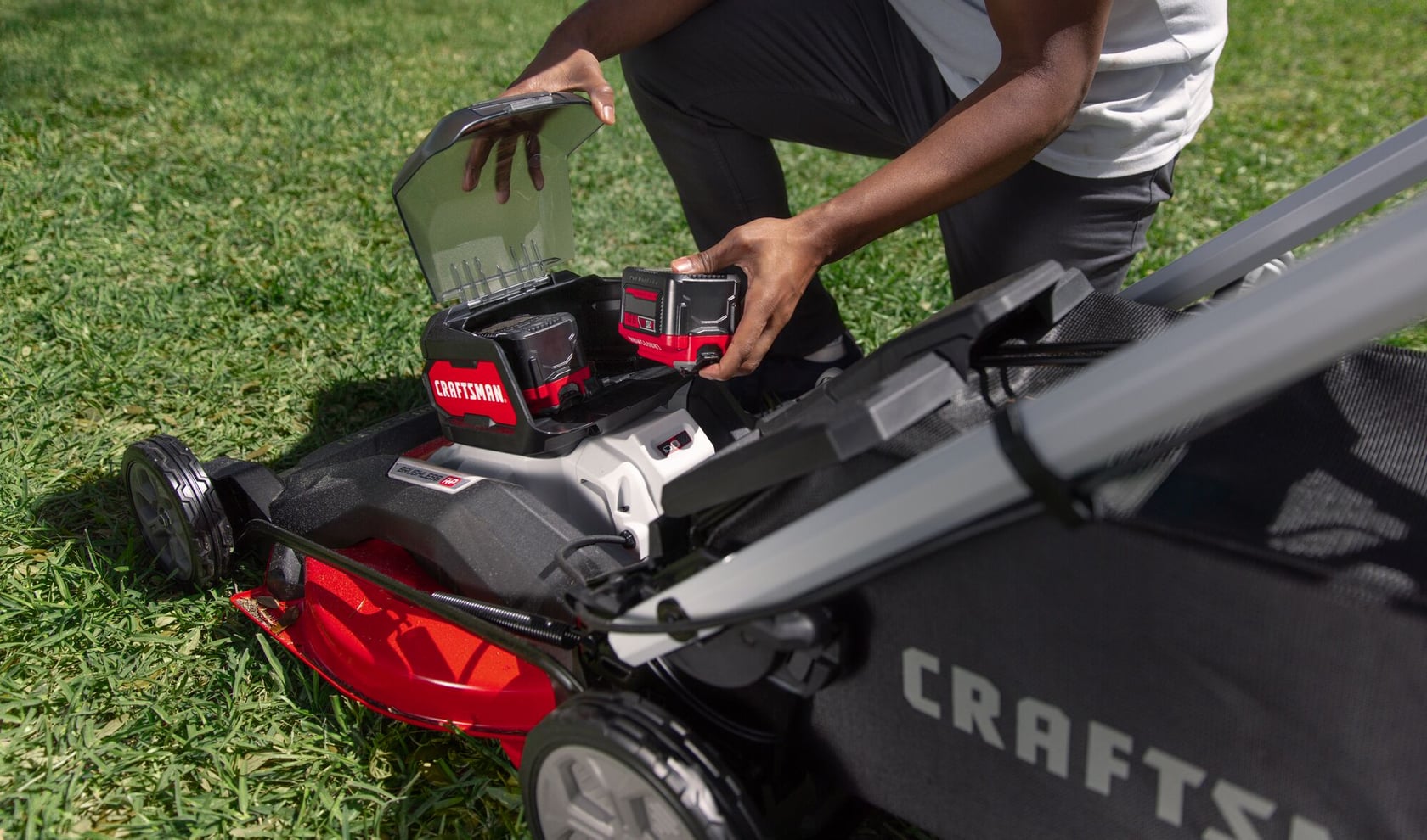 Photo of Craftsman lawn mower CMCMWSP320X2, battery compartment open, on grass, side angle.