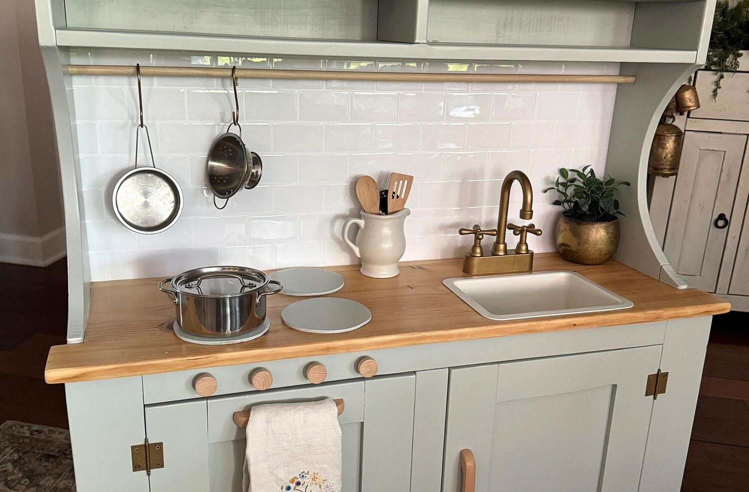 A grey and tan Kitchen with pots and pans around with a gold sink