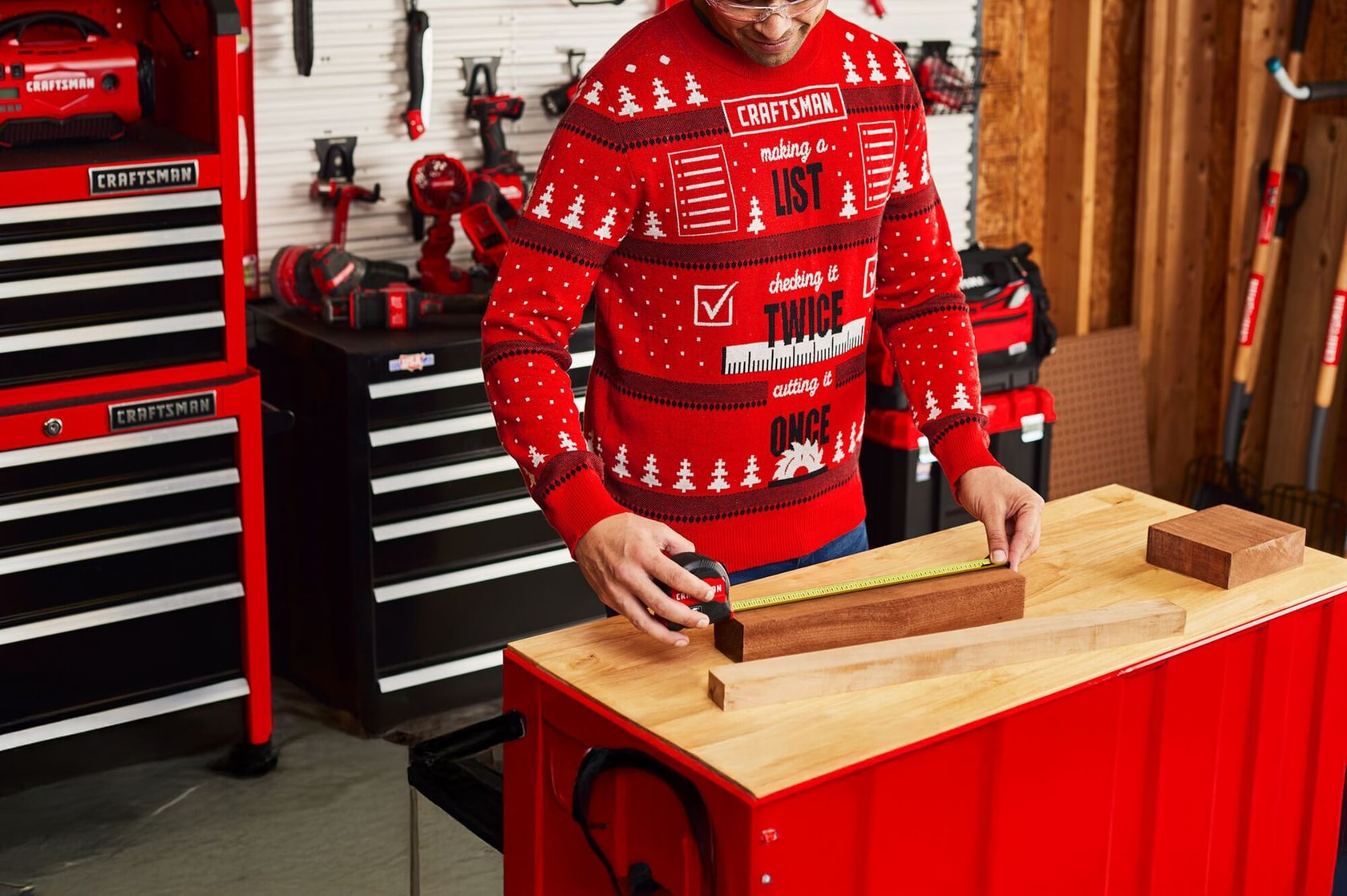Man wearing a CRAFTSMAN sweater working in a garage filled with craftsman storage units