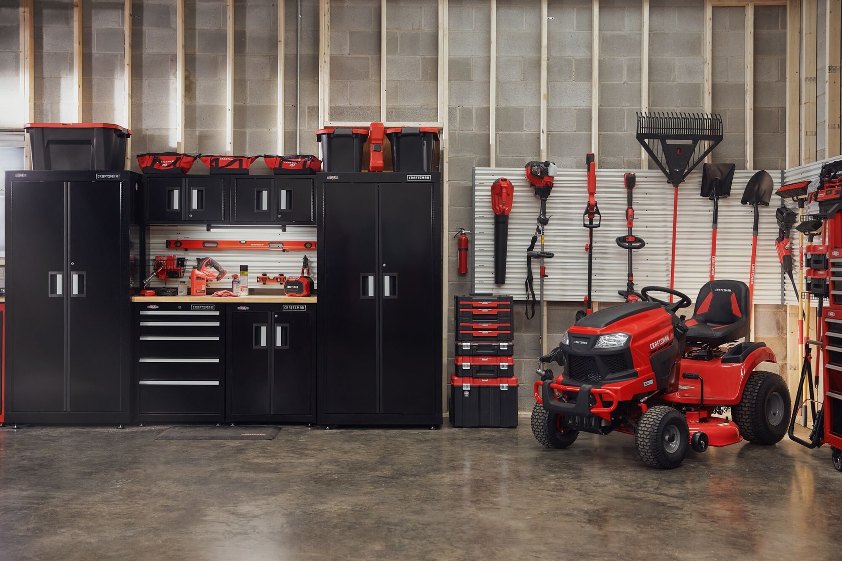 Photo of Craftsman CMCBL700D1 riding mower in garage with Craftsman tool cabinets and garden tools.