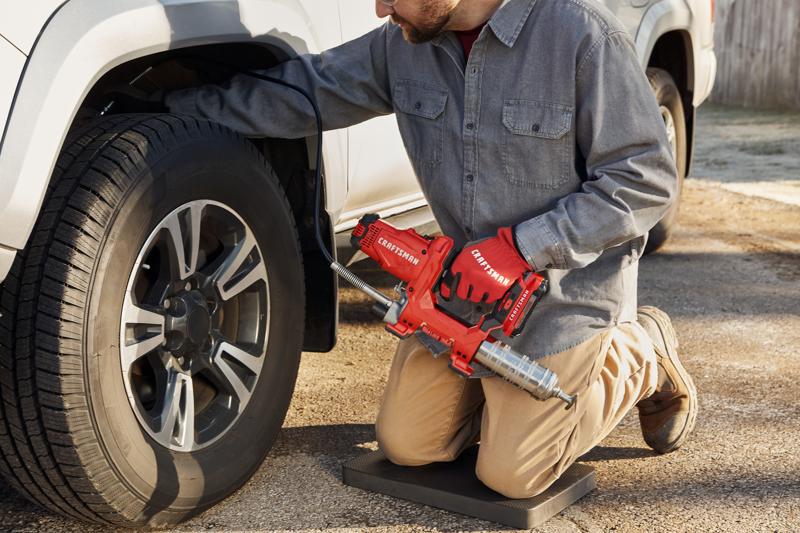 Photo of end-user applying grease with grease gun to farm equipment.