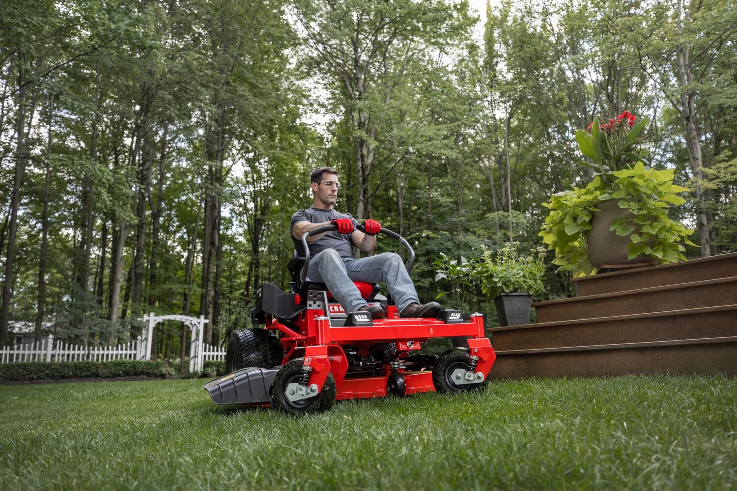 CRAFTSMAN Gas Zero-Turn cutting grass around deck steps with white archway in background