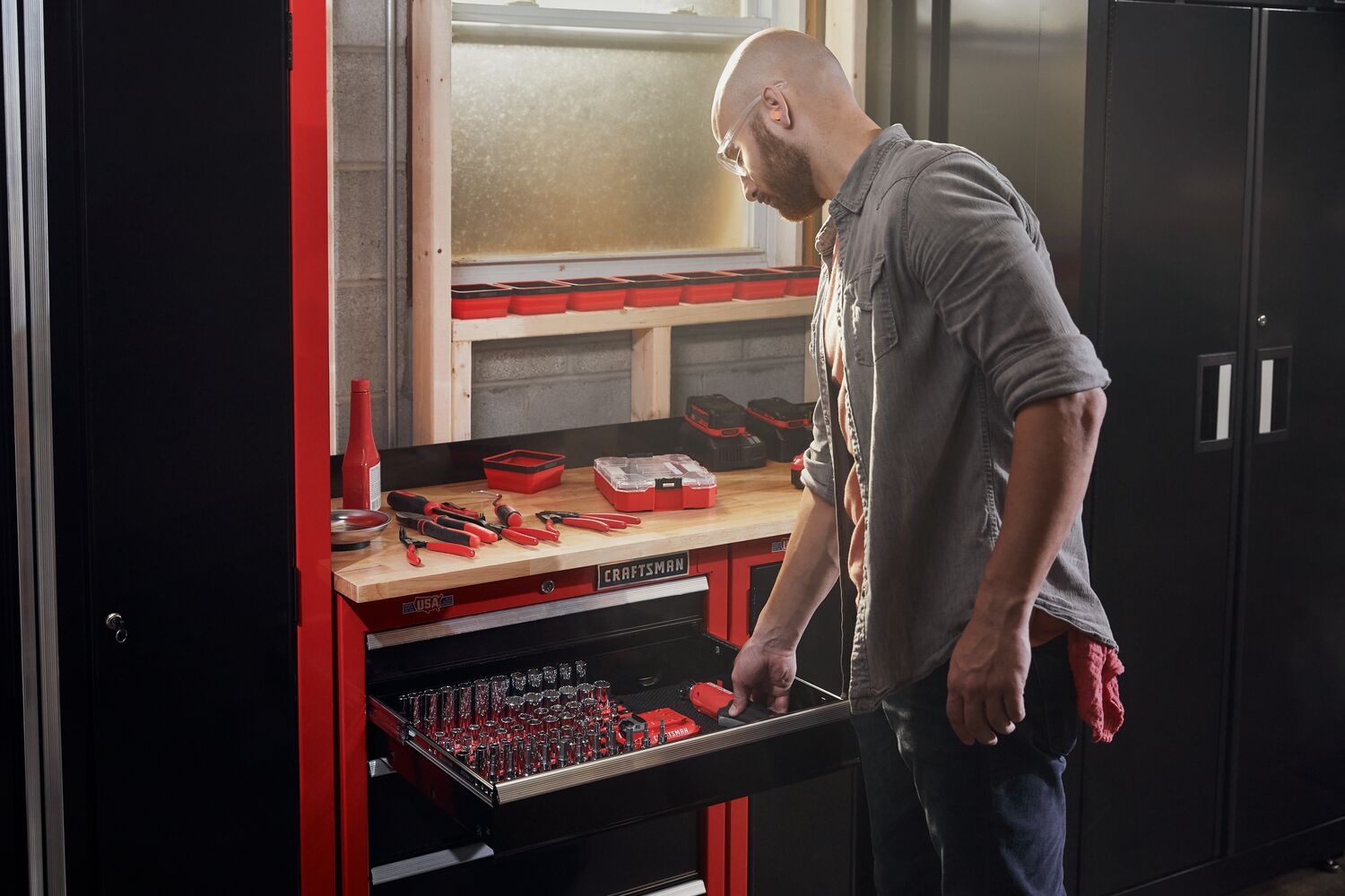 Man storing a CRAFTSMAN V20* ratchet inside Craftsan storage with an assortment of hand tools laying on top
