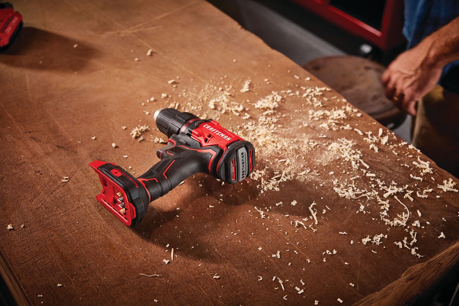 Cordless brushless half inch drill and driver kit 1 battery placed on wooden table with wood dust around.