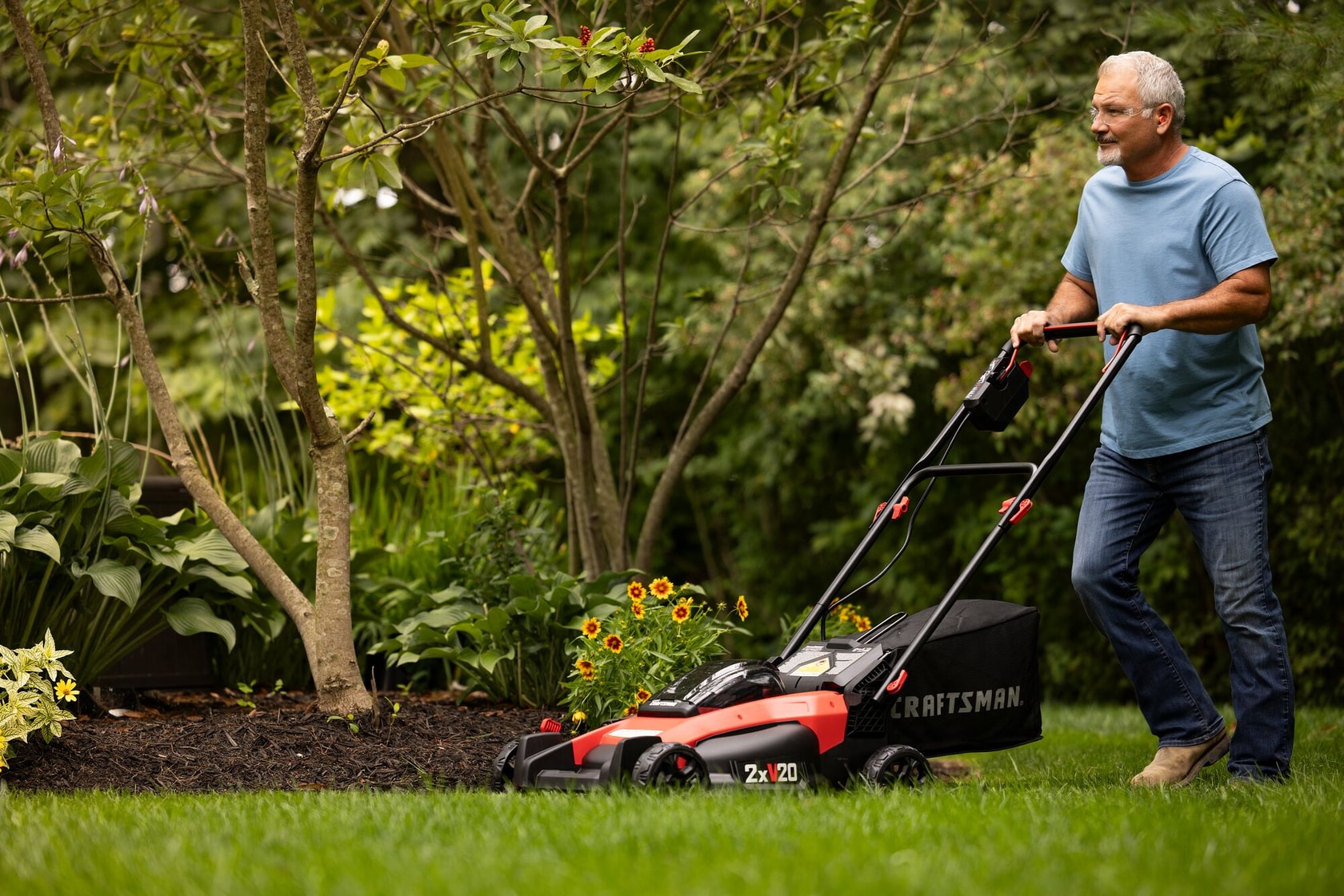 2 x 20 volt 20 inch brushless cordless push mower being used for mowing under bench.