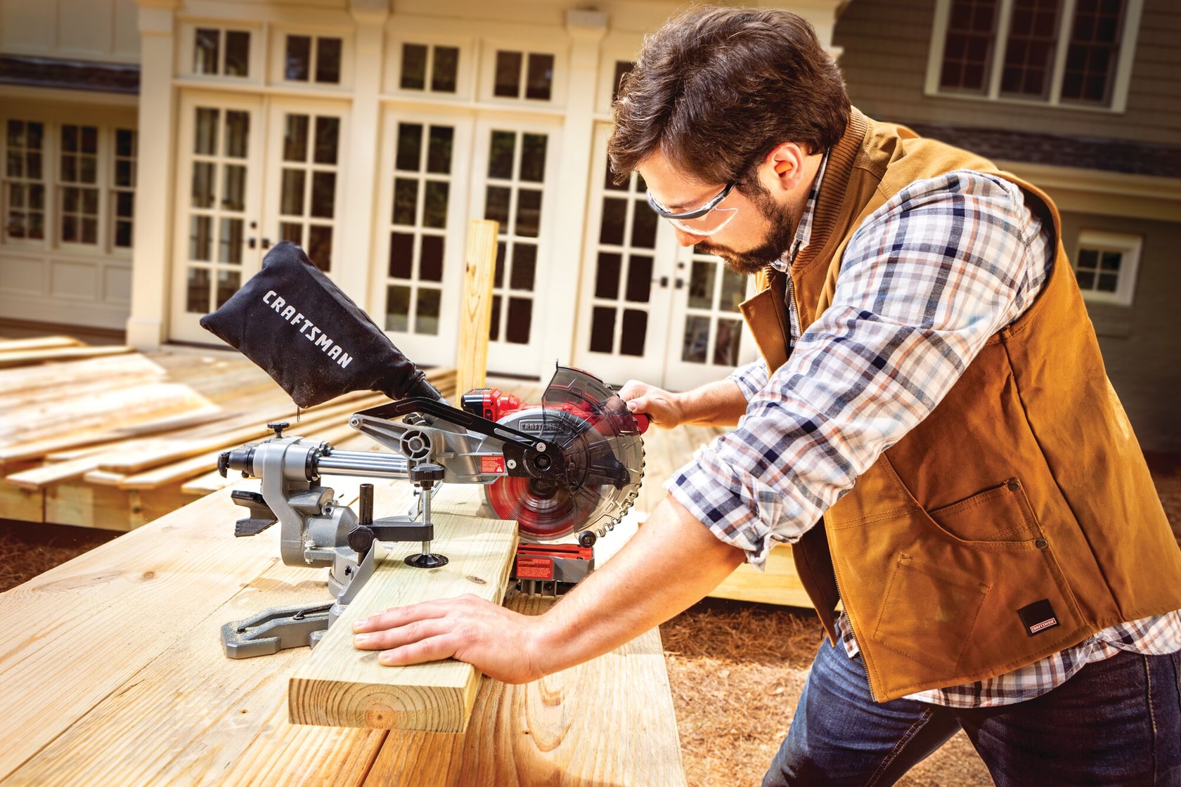 20 volt cordless 7 1 quarter inch sliding miter saw kit being used by a person to cut a wooden plank.
