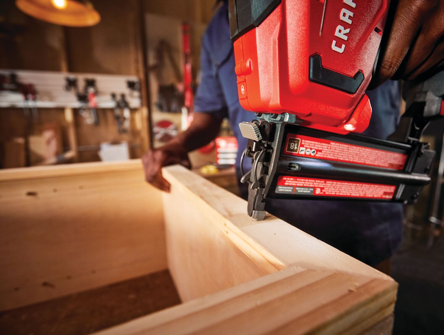 20 volt 18 gauge cordless brad nailer kit being used by a person on a wooden box indoors.