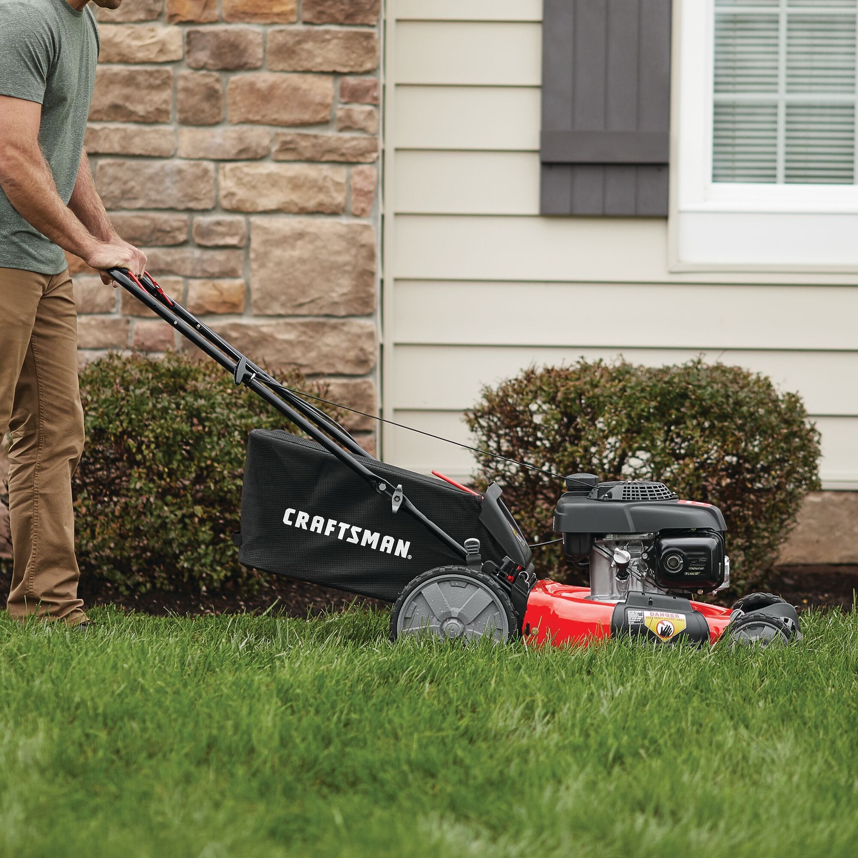 21 inch 160 c c honda push mower being used to mow the lawn in front of a house.