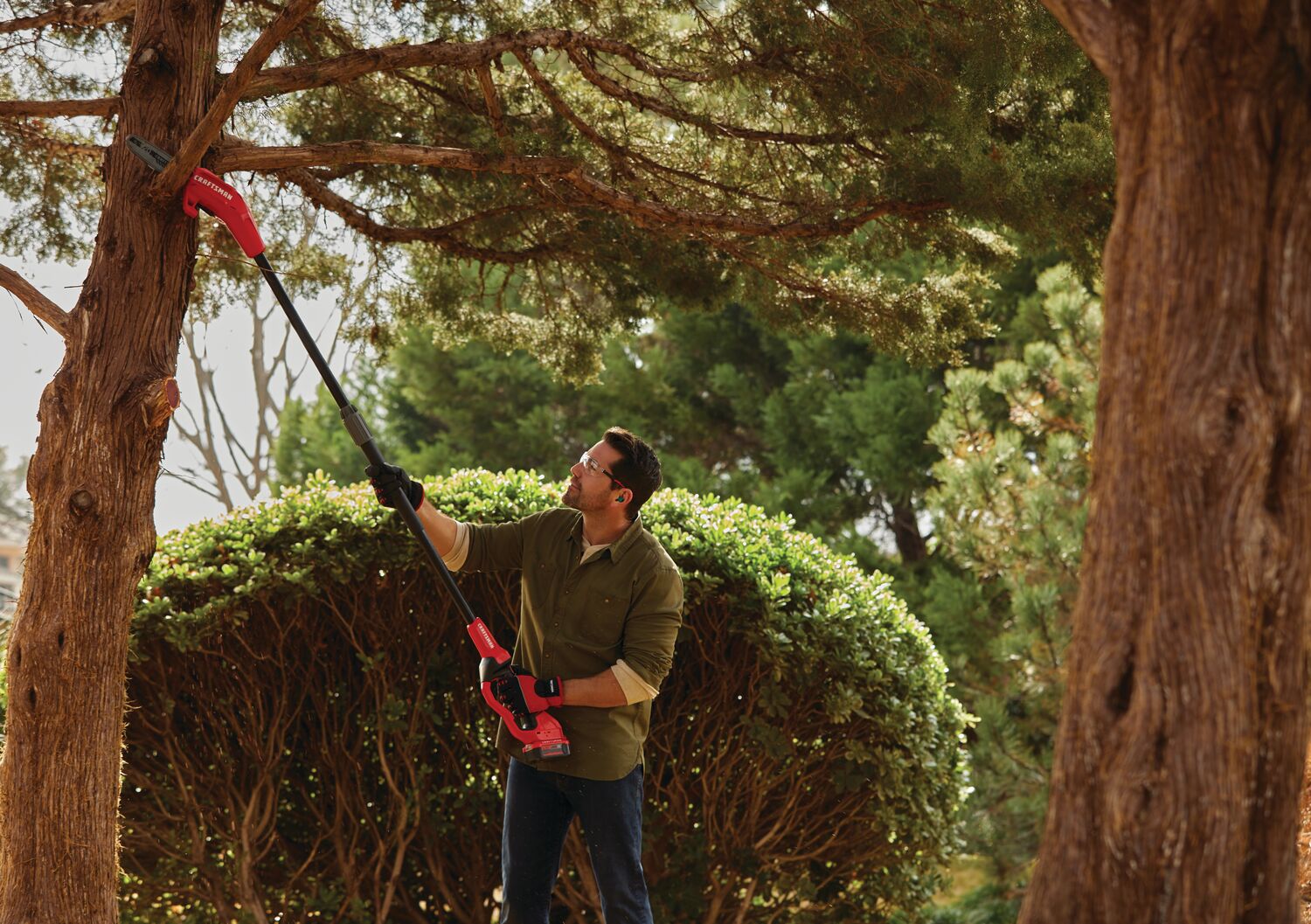 Cordless pole chainsaw kit 4 amp hour being used for cutting tree branch.
