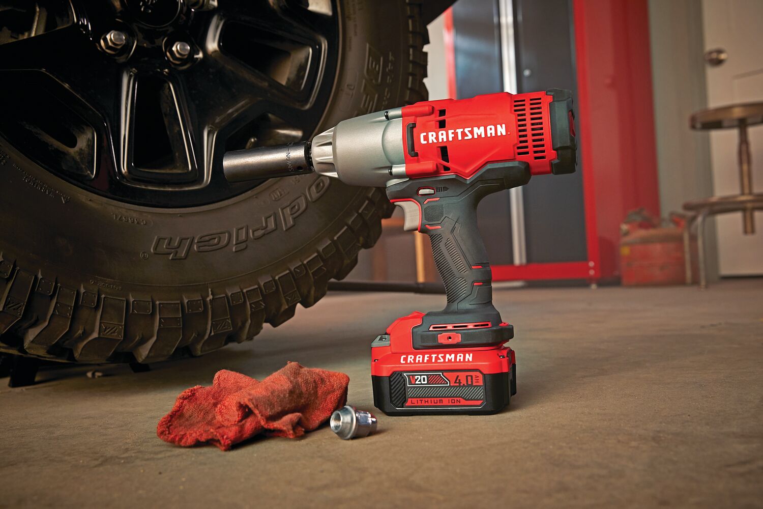 Cordless half inch impact wrench kit 1 battery placed on ground next to car tyre.