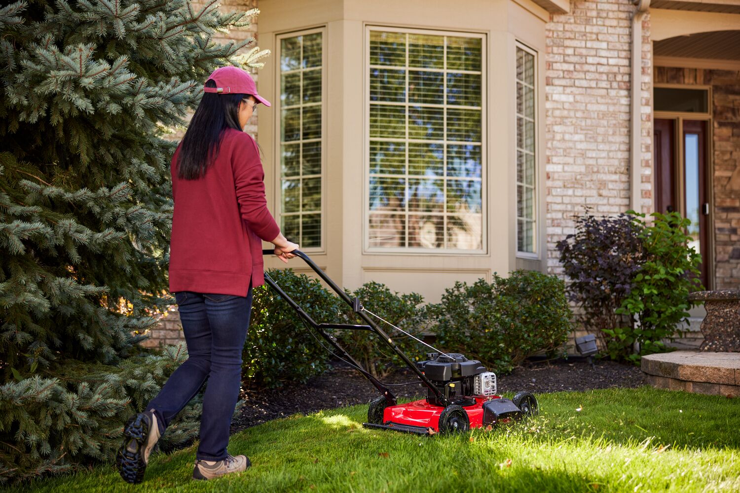 Behind view of woman cutting grass with M090 Walk-behind Lawn Mower